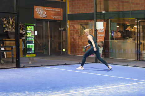 Padel speler die de bal speelt op de indoor banen in Leiden