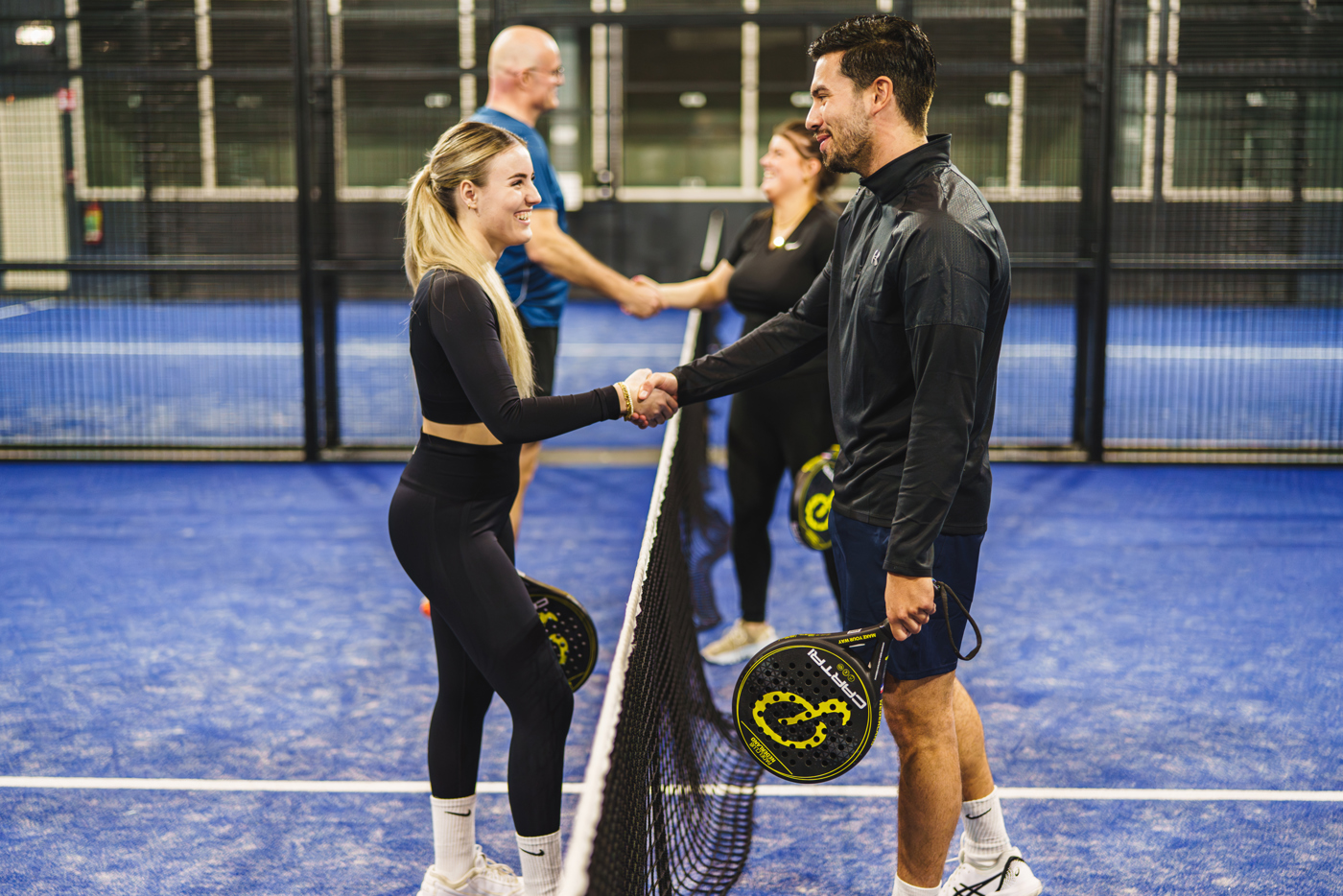 Vier padelspelers die elkaar de hand schudden op het veld bij Padelclub Nederland locatie Druten