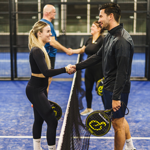 Vier padelspelers die elkaar de hand schudden na een wedstrijd op de padelbaan bij Padelclub Nederland