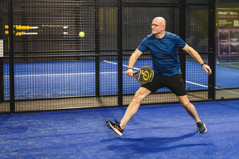 Padel speler bij Padelclub Nederland Druten smasht een bal over de padelbaan